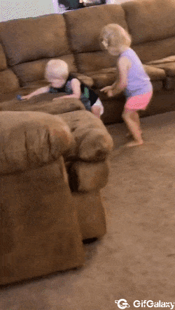 Little girl checks her younger brother's diaper